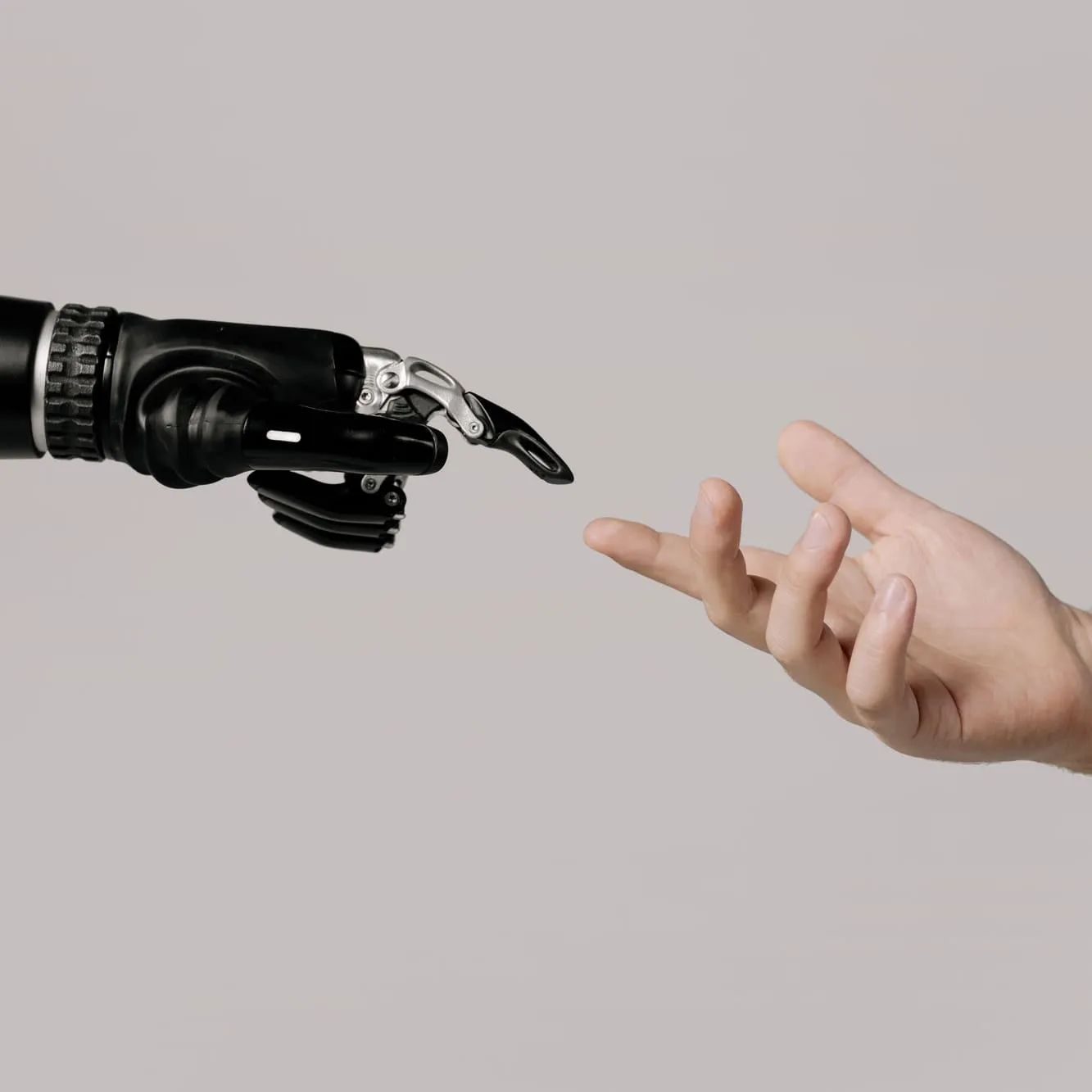 Eine Roboterhand und eine menschliche Hand strecken sich einander entgegen.